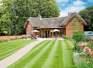 Manicured gardens and lawns in front of the thatched village shop and café at Richmond Letcombe Regis