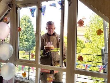 A burly fireman arriving with a cake in hand. Photo courtesy of Addison Court.