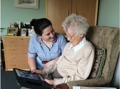Westacres care home resident, Rita with care worker Louise, using Storii to look at photos of her grandson