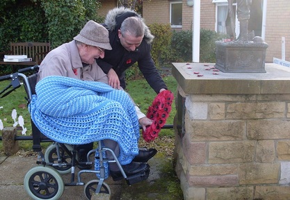 Care home resident lays a poppy wreath at Hattonlea care home's war memorial