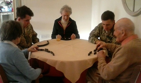 Left-right: Trooper Stephen Dixon and Private Burnikell play dominos with residents Credit: Daniel Burnikell