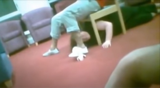 Footage of care worker restraining a patient under a chair at Winterbourne View. Credit: YouTube/BBC