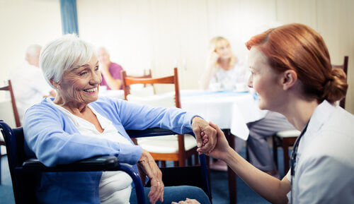 A carer provides an older lady with residential care in a care home