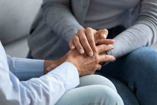 Care worker compassionately holding an elderly care home resident's hand during person-centred end of life care